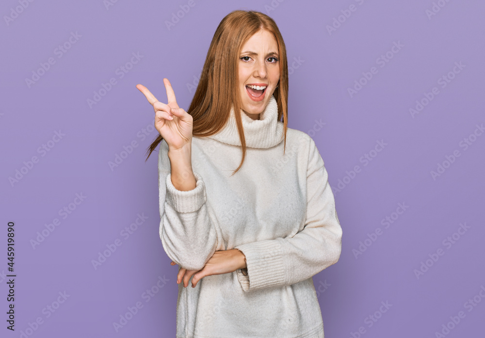 Young irish woman wearing casual winter sweater smiling with happy face winking at the camera doing victory sign with fingers. number two. Young irish woman wearing casual winter sweater smiling with happy face winking at the camera doing victory sign with fingers. number two.