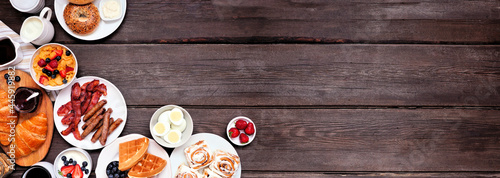 Breakfast or brunch corner border on a dark wood banner background. Above view. Different sweet and savory food items.