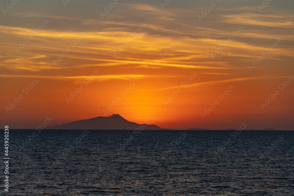 Beautiful sunset with sun hiding behind Ischia island over Tyrrhenian Sea