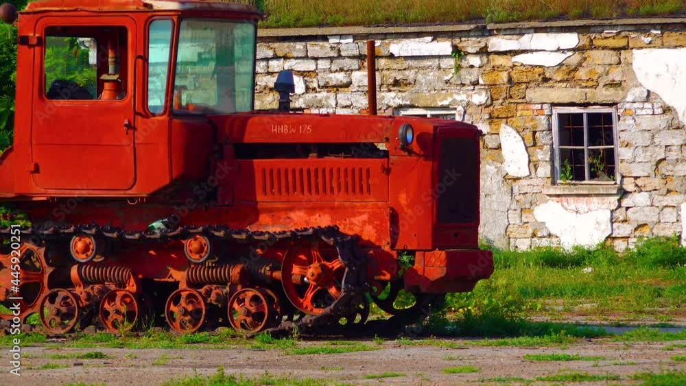 Old red tractor on the background of a destroyed building, Ukraine Old red tractor on the background of a destroyed building, Ukraine