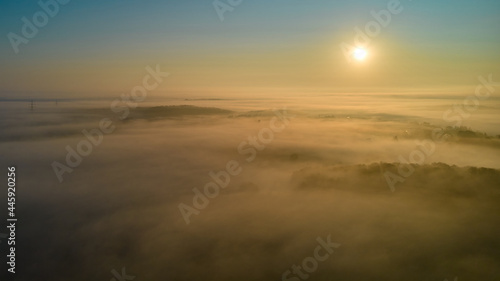 In the morning at sunrise above the fog. Landscape above a village between the forests. Aerial view.