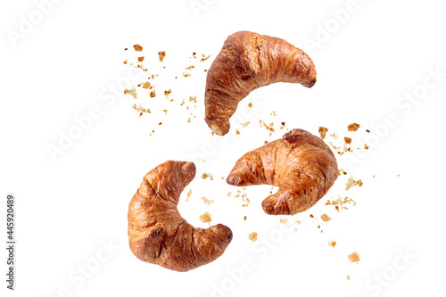 Fresh baked butter  breakfast croissants  with crumbs flying isolated on white