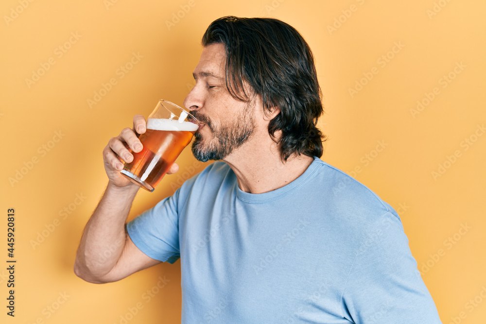 Middle age caucasian man with beard drinking a pint glass of fresh beer Middle age caucasian man with beard drinking a pint glass of fresh beer