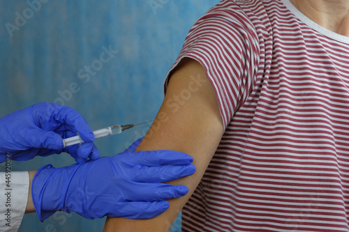 Close up of the hand of a general practitioner holding a vaccine injection. Flu shot. Doctor vaccinates the patient's shoulder