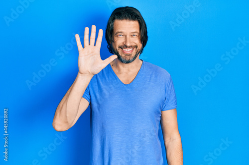 Middle age caucasian man wearing casual clothes showing and pointing up with fingers number five while smiling confident and happy.