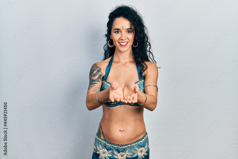 Young woman wearing bindi and traditional belly dance clothes smiling with hands palms together receiving or giving gesture. hold and protection Young woman wearing bindi and traditional belly dance clothes smiling with hands palms together receiving or giving gesture. hold and protection