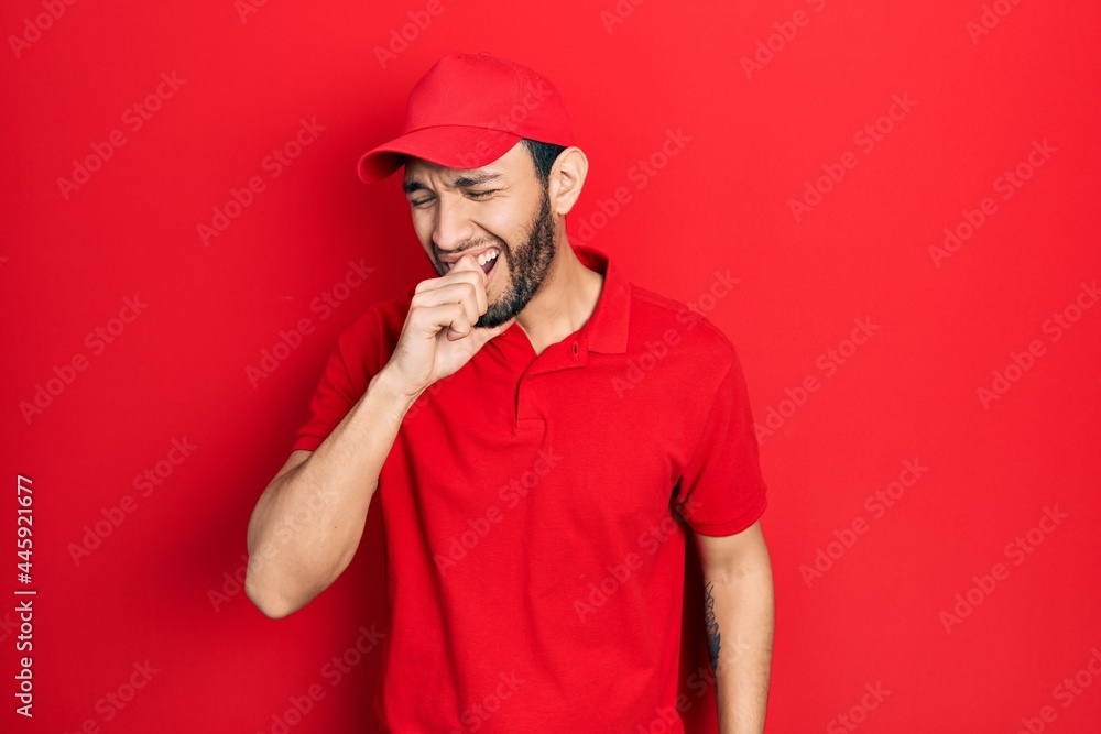 Hispanic man with beard wearing delivery uniform and cap feeling unwell and coughing as symptom for cold or bronchitis. health care concept. Hispanic man with beard wearing delivery uniform and cap feeling unwell and coughing as symptom for cold or bronchitis. health care concept.