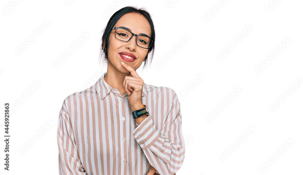 Young hispanic girl wearing casual clothes and glasses looking confident at the camera smiling with crossed arms and hand raised on chin. thinking positive.