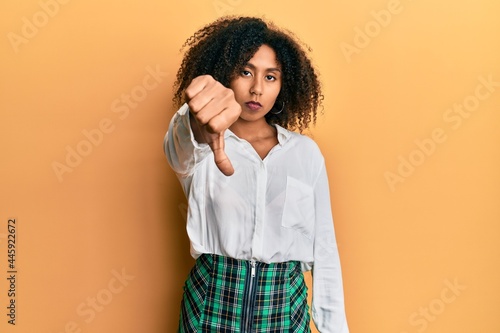 Beautiful african american woman with afro hair wearing scholar skirt looking unhappy and angry showing rejection and negative with thumbs down gesture. bad expression. © Krakenimages.com