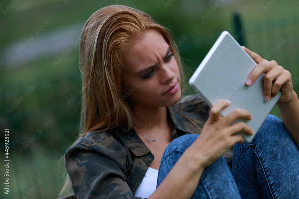 Concerned confused young woman staring at her tablet Concerned confused young woman staring at her tablet