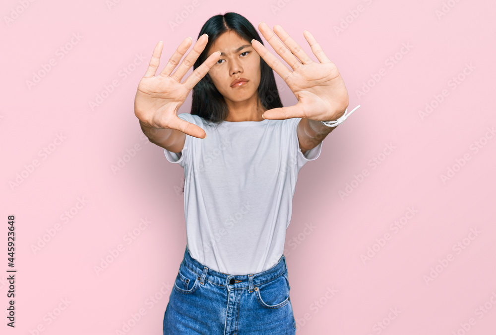 Beautiful young asian woman wearing casual white t shirt doing frame using hands palms and fingers, camera perspective Beautiful young asian woman wearing casual white t shirt doing frame using hands palms and fingers, camera perspective