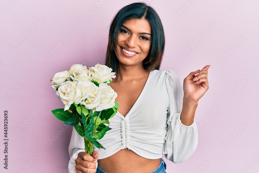 Young latin transsexual transgender woman holding flowers smiling happy pointing with hand and finger to the side Young latin transsexual transgender woman holding flowers smiling happy pointing with hand and finger to the side