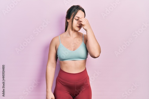 Young hispanic girl wearing sportswear tired rubbing nose and eyes feeling fatigue and headache. stress and frustration concept.
