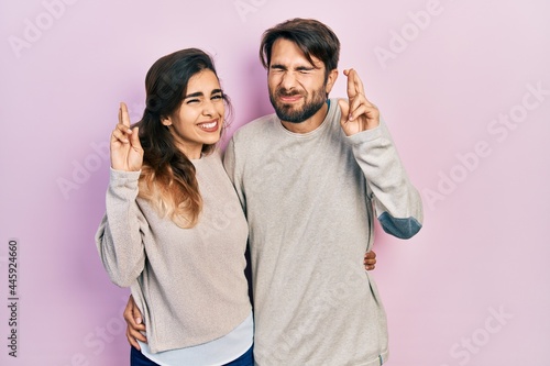 Young hispanic couple wearing casual clothes gesturing finger crossed smiling with hope and eyes closed. luck and superstitious concept.