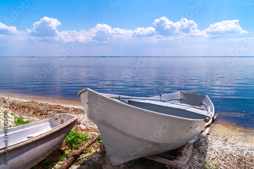 white fishing boat rest on shore. old rusty winch and boat on beach. beautiful summer landscape on the river or lake or sea. Boat on the river bank.