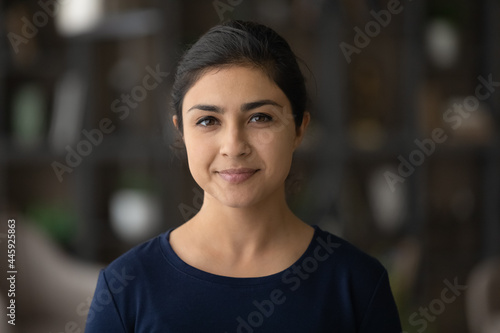 Headshot portrait of happy millennial Indian woman look at camera posing in own house or apartment. Profile picture of smiling young mixed race female renter tenant. Rent, real estate concept.