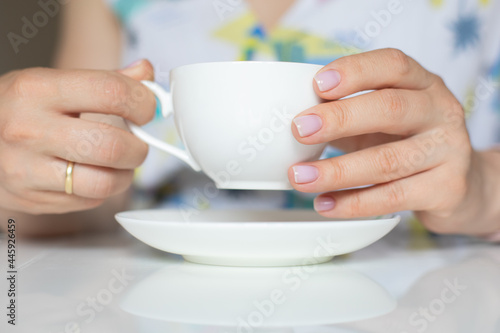 The concept of self-care, beauty. Women's hands with a neat manicure of nude color. Fingers holding a cup of tea.