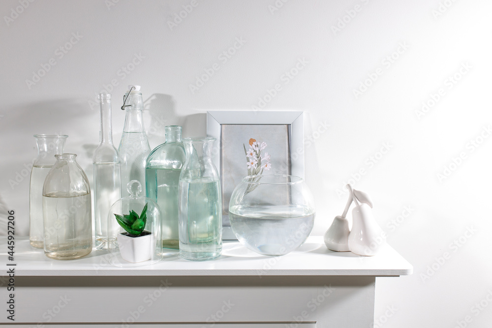 A set of water bottles of different shapes with a photo frame and a pot with artificial succulent is on the dresser A set of water bottles of different shapes with a photo frame and a pot with artificial succulent is on the dresser