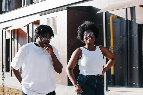 two happy African-American women are walking down the street in the summer