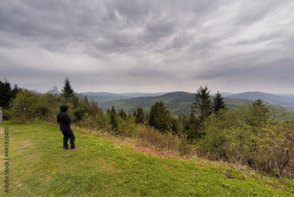 Fototapeta premium Wielki Lubon, Poland : An unidentified man in black clothes standing by the cliff admiring view of Lubon Wielki mountain located in Poland during overcast cloudy weather.