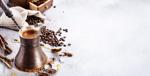 Turkish coffee brewing pot and beans on concrete background with copy space photo