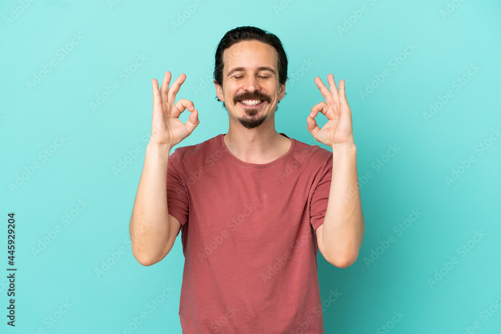 Young caucasian man isolated on blue background in zen pose Young caucasian man isolated on blue background in zen pose