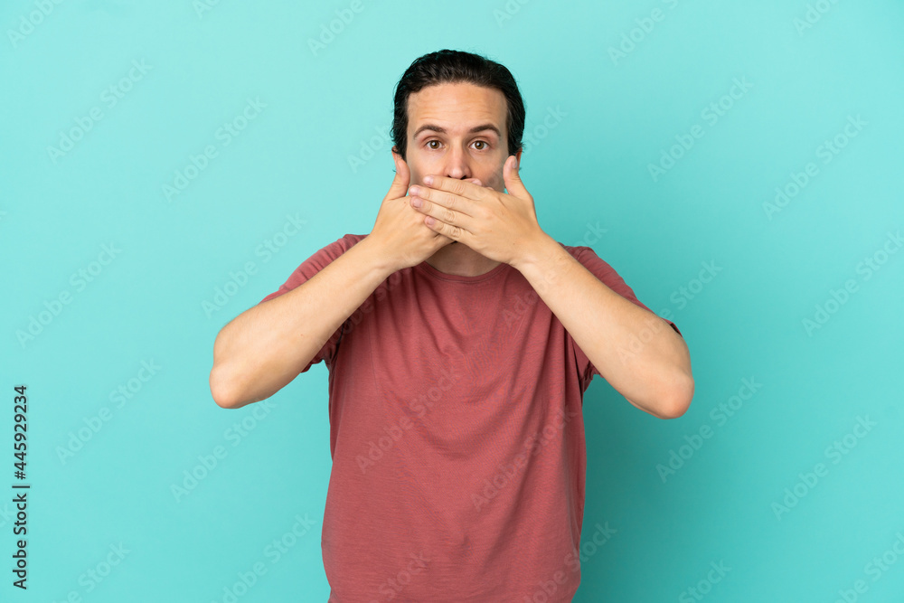 Young caucasian man isolated on blue background covering mouth with hands Young caucasian man isolated on blue background covering mouth with hands