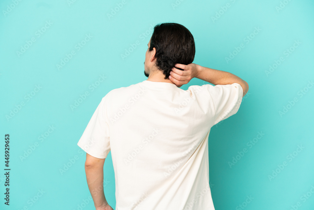 Young caucasian man isolated on blue background in back position and thinking Young caucasian man isolated on blue background in back position and thinking