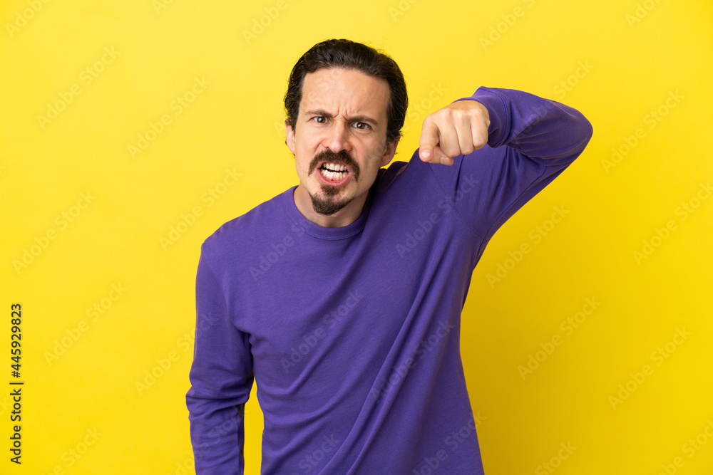 Young caucasian man isolated on yellow background frustrated and pointing to the front Young caucasian man isolated on yellow background frustrated and pointing to the front