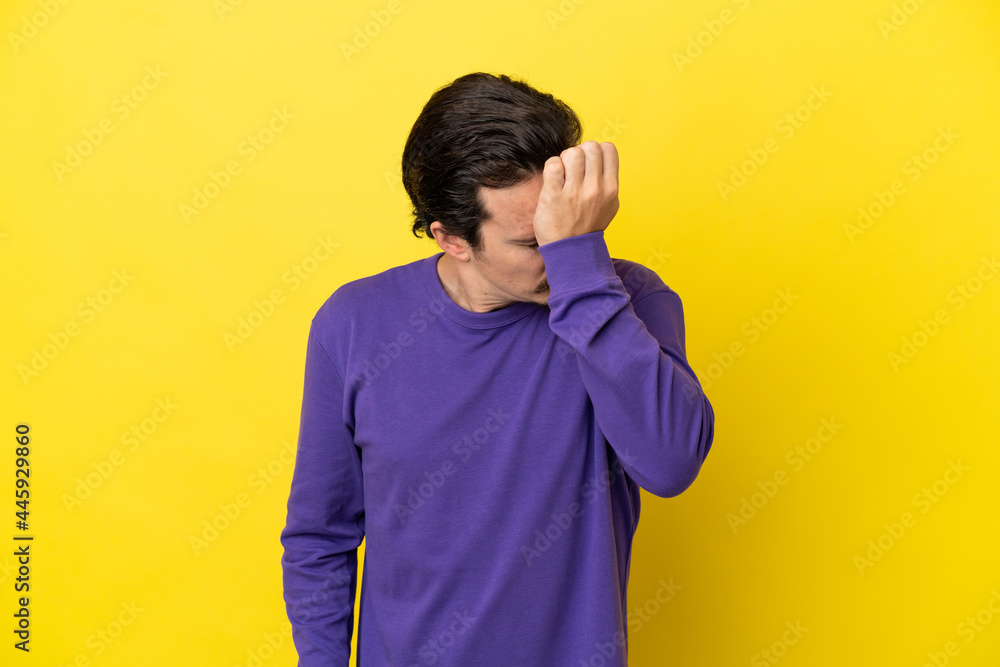 Young caucasian man isolated on yellow background with headache Young caucasian man isolated on yellow background with headache