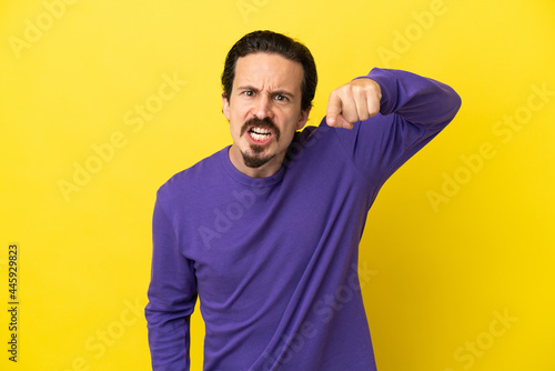 Young caucasian man isolated on yellow background frustrated and pointing to the front