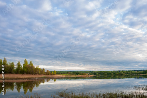 Autumn landscape with lake, trees with yellow leaves and sky with beautiful clouds.
