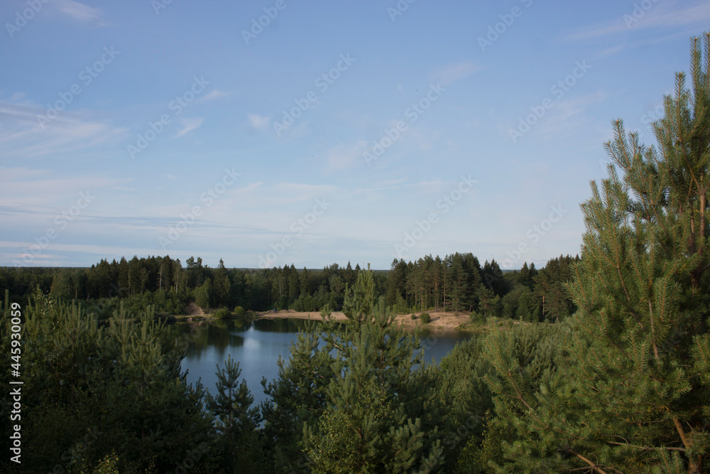 Summer landscape with a beautiful lake with fir trees and forested mountains against a cloudy sky Summer landscape with a beautiful lake with fir trees and forested mountains against a cloudy sky