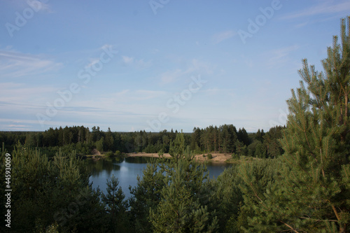 Summer landscape with a beautiful lake with fir trees and forested mountains against a cloudy sky