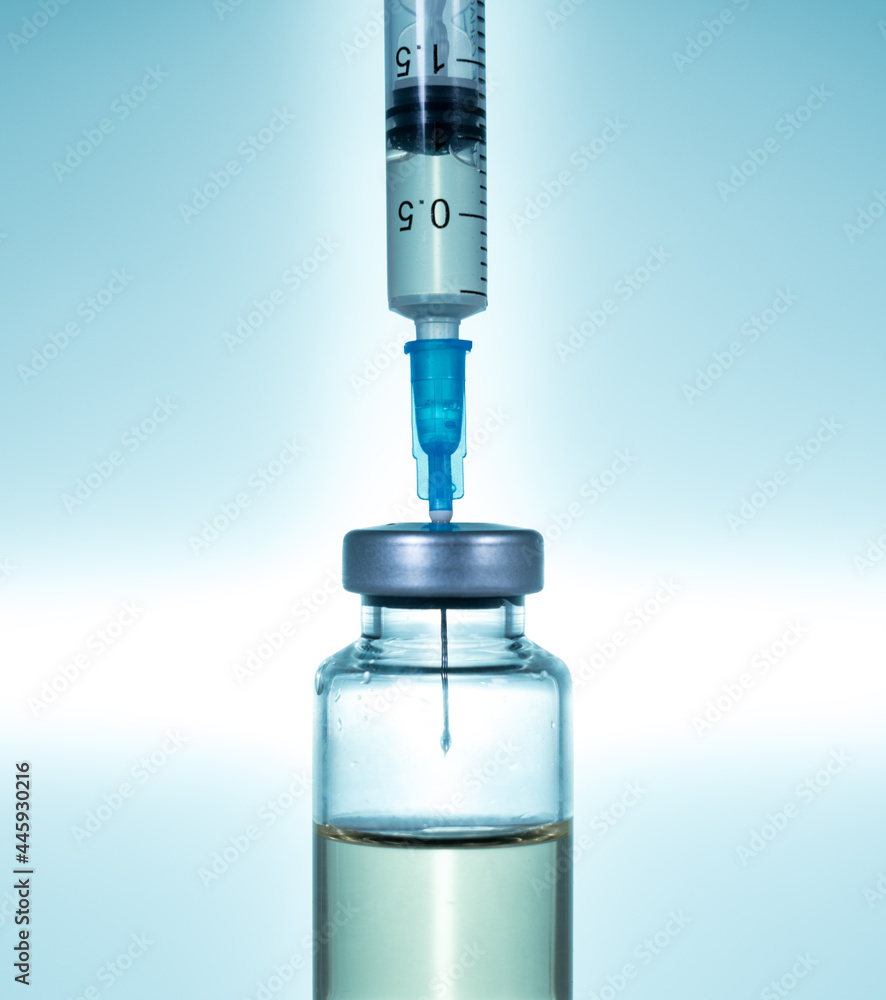 Macro of a hypodermic syringe or needle being filled with vaccine from bottle against a blue star background Macro of a hypodermic syringe or needle being filled with vaccine from bottle against a blue star background