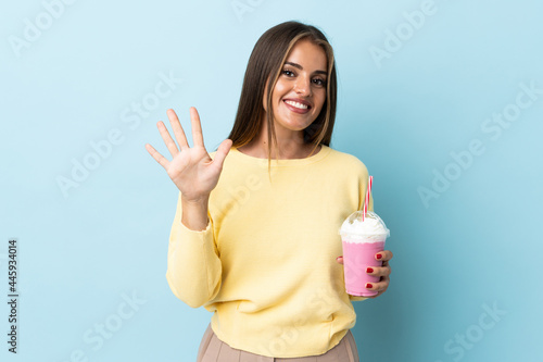 Young Uruguayan woman with strawberry milkshake isolated on blue background counting five with fingers