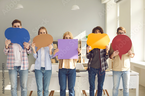 Group of college students holding multicolored empty cardboard and paper mockup speech bubbles covering their faces. Concept of young people expressing opinion and putting message across
