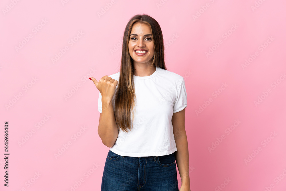 Young Uruguayan woman isolated on pink background pointing to the side to present a product Young Uruguayan woman isolated on pink background pointing to the side to present a product