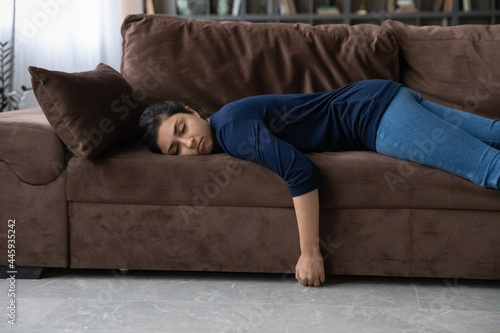 Obraz na plátně Exhausted millennial Indian woman lying on sofa in living room sleep or take nap after hard day