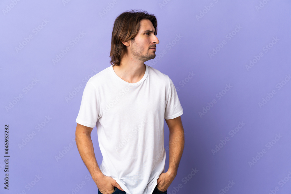 Young handsome man isolated on purple background looking to the side Young handsome man isolated on purple background looking to the side