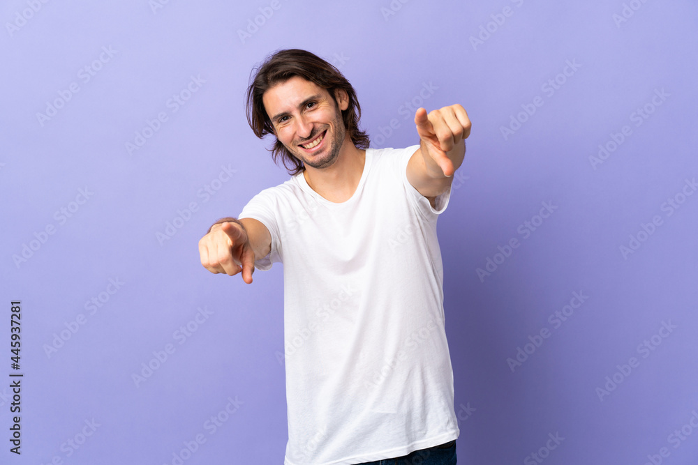 Young handsome man isolated on purple background pointing front with happy expression Young handsome man isolated on purple background pointing front with happy expression