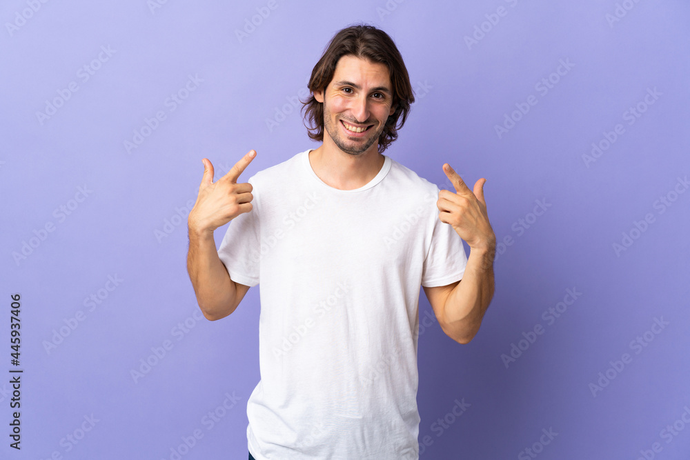 Young handsome man isolated on purple background giving a thumbs up gesture