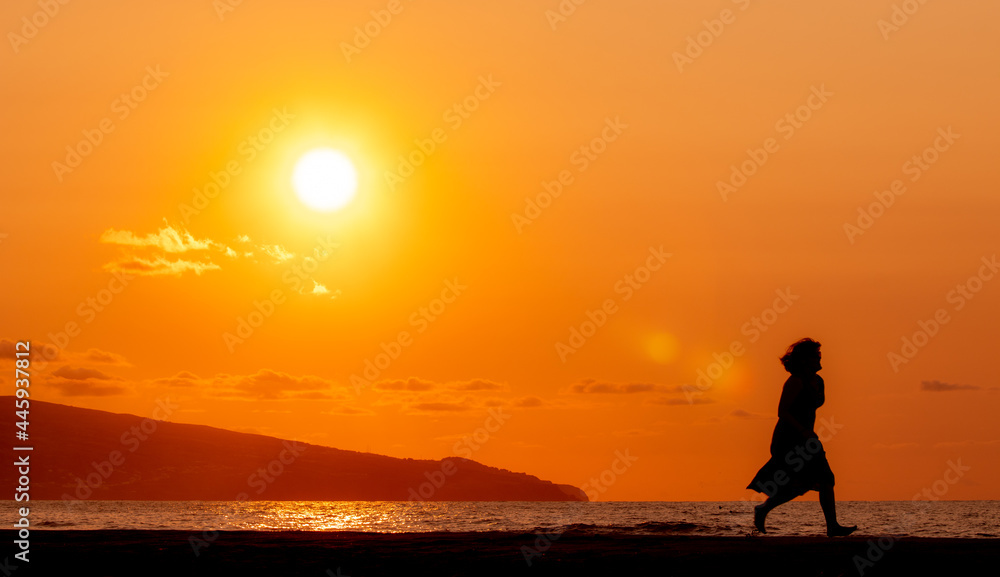 Woman at beach, during sunset, silhouette.