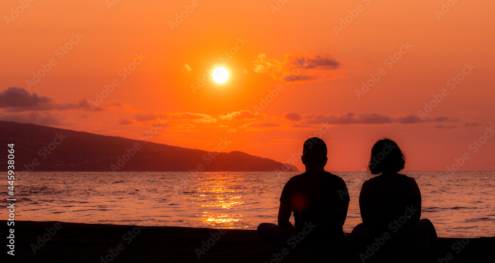 Harmony between couple at the beach, silhouette during sunset, lovers.