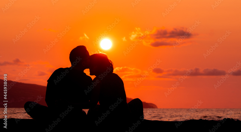 Harmony between couple at the beach, silhouette during sunset, lovers.