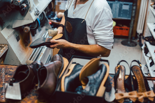 Shoemaker with shoes to repair on a rack in his workshop seen from above