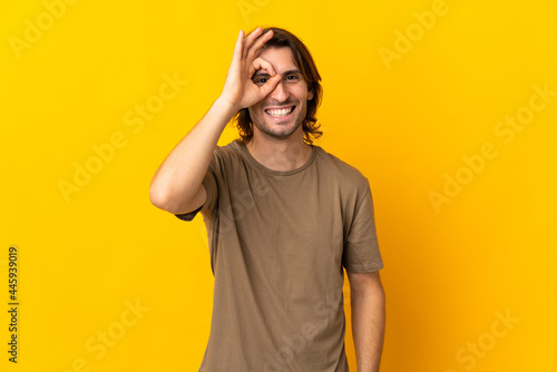 Young handsome man isolated on yellow background showing ok sign with fingers © luismolinero