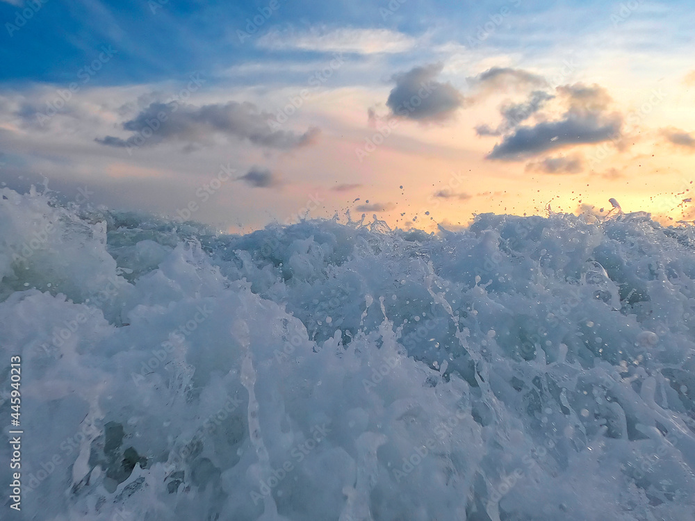 Naklejka premium Evening scenery on the beach, waves and water foam on the Pacific or carribean ocean coast bay with dramatic clouds on the sky, holidays in paradise. Sea and sunset or sunrise