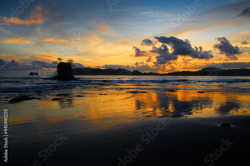 Evening scenery on the beach in Nicoya peninsula, Costa Rica. Pacific ocean coast bay with dramatic clouds on the sky, holidays in paradise. Trees, island, sea and sunset or sunrise, beautiful sky photo