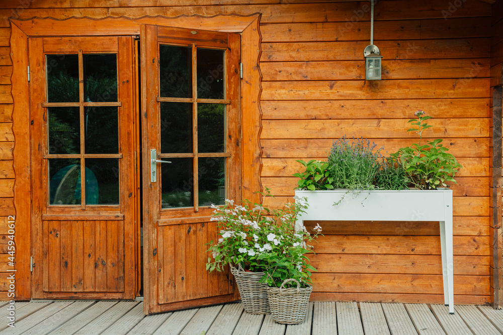 Raised bed with plants and flowers next to a wooden house in the garden. Hydrangea and lavender in a raised bed in summer. Beautiful plants in front of a wooden hut Raised bed with plants and flowers next to a wooden house in the garden. Hydrangea and lavender in a raised bed in summer. Beautiful plants in front of a wooden hut